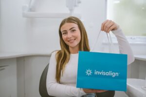 Smiling Invisalign patient holding an Invisalign bag at Lodge Causeway Dental Centre in Bristol