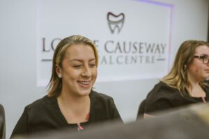 Smiling receptionist welcoming patients at the reception desk of Lodge Causeway Dental Centre in Bristol