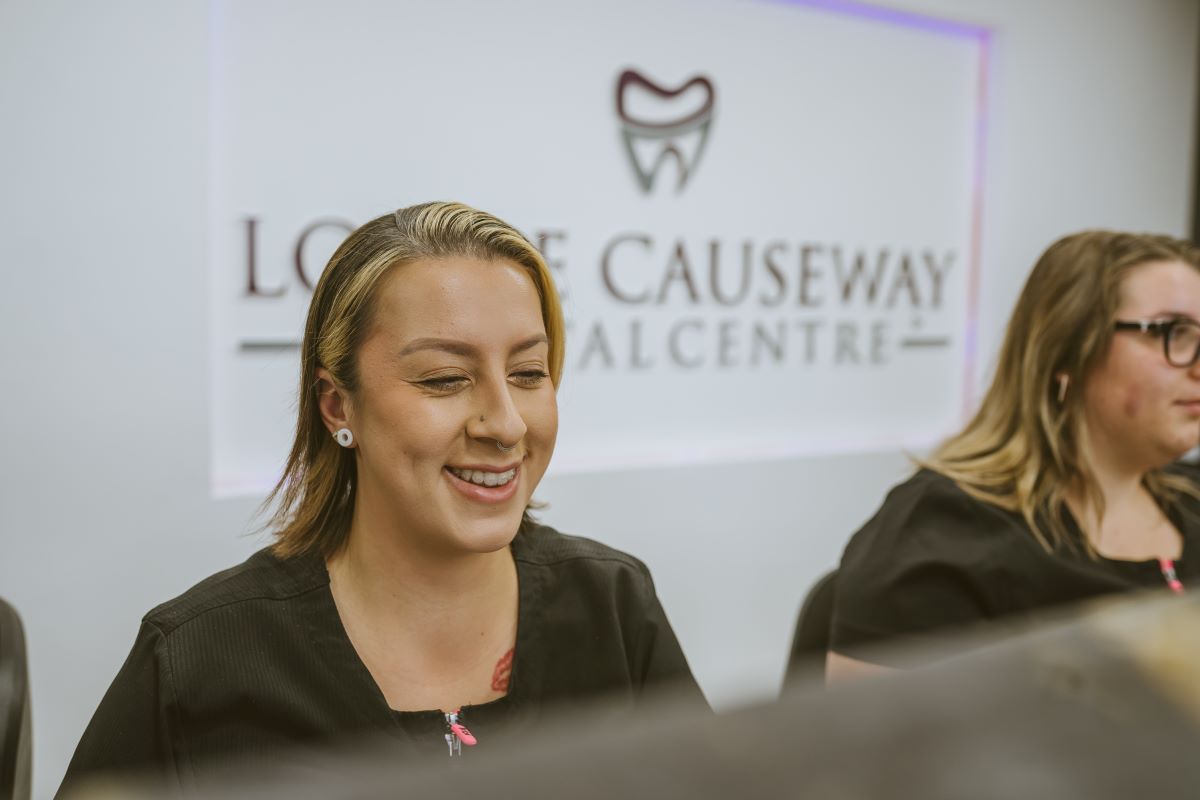 Smiling receptionist welcoming patients at the reception desk of Lodge Causeway Dental Centre in Bristol