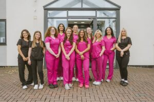 Team of dental nurses in pink and black uniforms outside Lodge Causeway Dental Centre in Fishponds
