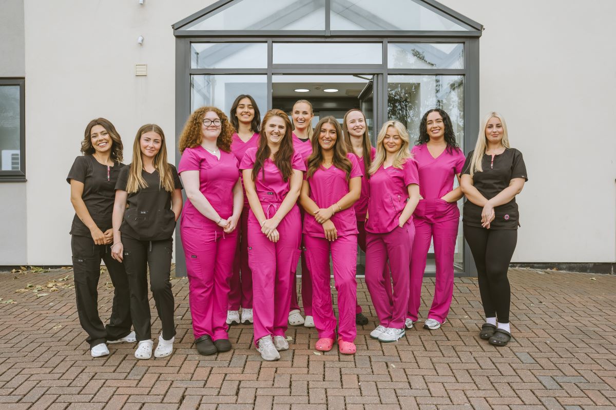 Team of dental nurses in pink and black uniforms outside Lodge Causeway Dental Centre in Fishponds