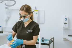 Cosmetic dentist using magnification loupes while carefully performing composite bonding treatment on a patient