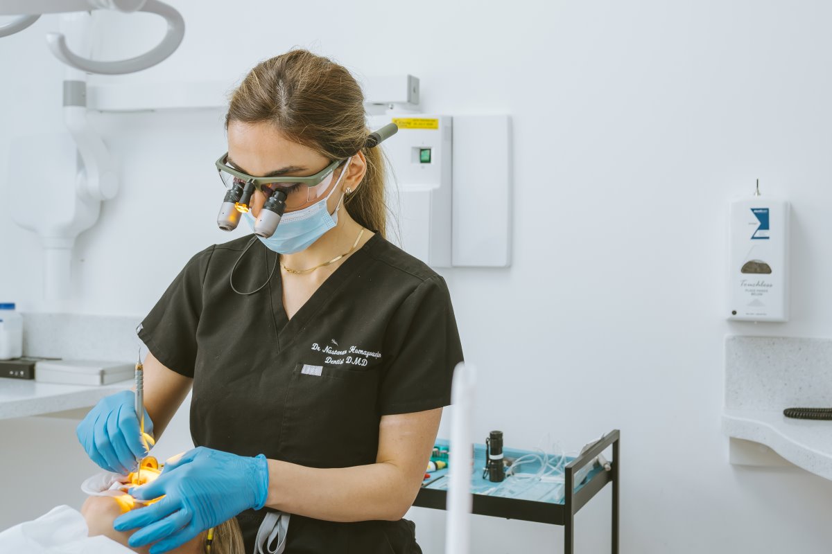Cosmetic dentist using magnification loupes while carefully performing composite bonding treatment on a patient