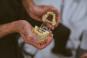 Close-up of a dentist using a dental model to explain missing-tooth replacement and dental implant treatment