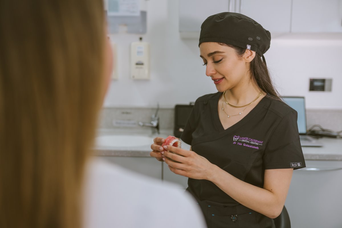 Dentist using a dental model to explain how Invisalign clear aligners move the teeth during treatment