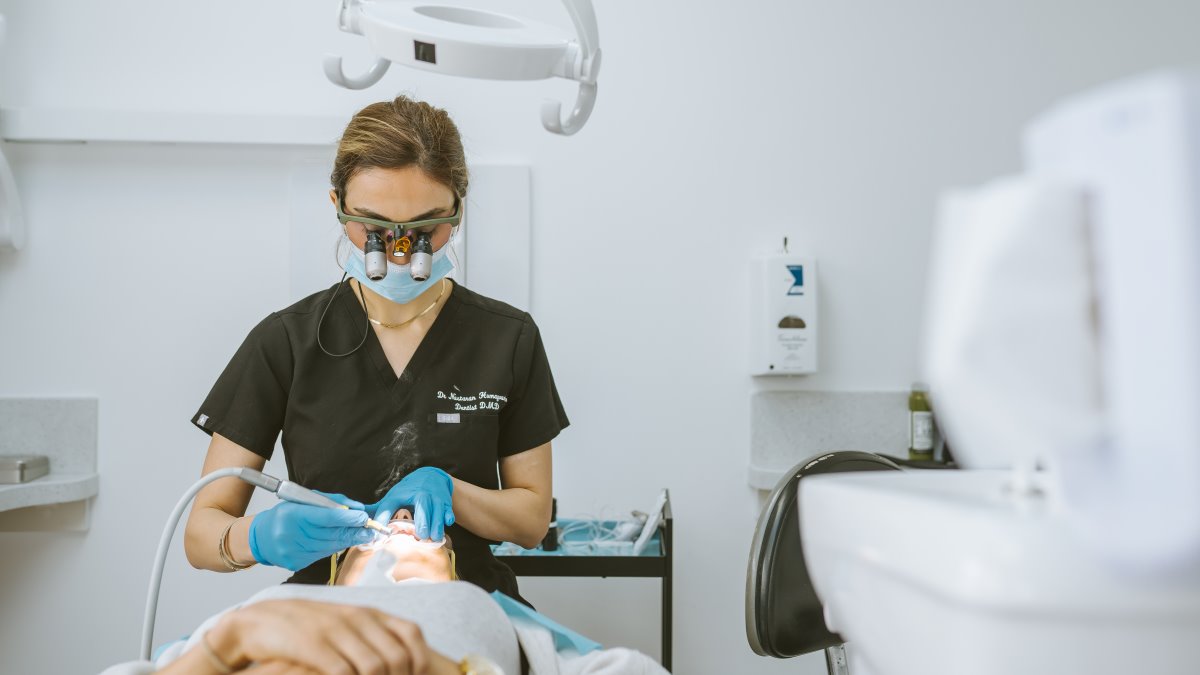 Dentist precisely shaping and finishing composite bonding material on a patient’s teeth in the dental clinic
